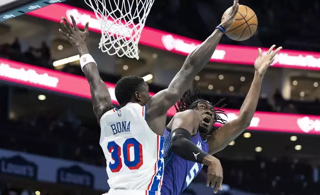 Charlotte Hornets center Mark Williams, right, shoots against Philadelphia 76ers center Adem Bona (30) during the first half of an NBA Cup basketball game in Charlotte, N.C., Tuesday, Dec. 3, 2024. (AP Photo/Nell Redmond)