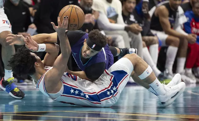 Charlotte Hornets guard Seth Curry, top, battles Philadelphia 76ers guard Jared McCain for a loose ball during the first half of an NBA Cup basketball game in Charlotte, N.C., Tuesday, Dec. 3, 2024. (AP Photo/Nell Redmond)