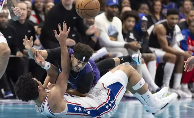 Charlotte Hornets guard Seth Curry, top, battles Philadelphia 76ers guard Jared McCain for a loose ball during the first half of an NBA Cup basketball game in Charlotte, N.C., Tuesday, Dec. 3, 2024. (AP Photo/Nell Redmond)