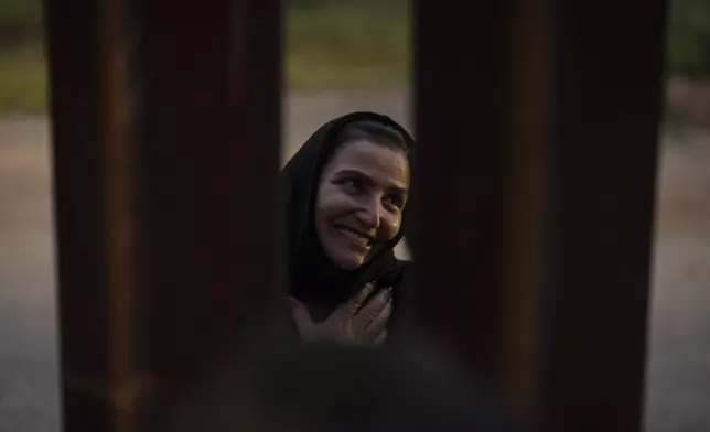 Georgian migrant Nani smiles as she thanks a U.S. volunteer, speaking between gaps in one of the border walls separating Tijuana, Mexico, and San Diego, as she waits to apply for asylum with U.S. authorities, Friday, April 12, 2024, seen from San Diego. (AP Photo/Gregory Bull)