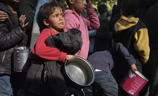 Palestinian children queue for food in Deir al-Balah, Gaza Strip, Friday, Dec. 13, 2024. (AP Photo/Abdel Kareem Hana)