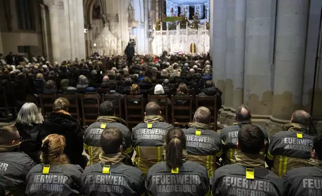 Firefighters, in the foreground, and others, attend a memorial service for victims of Friday's Christmas Market attack, where a car drove into a crowd, in Magdeburg, Germany, Saturday, Dec. 21, 2024. (AP Photo/Ebrahim Noroozi)