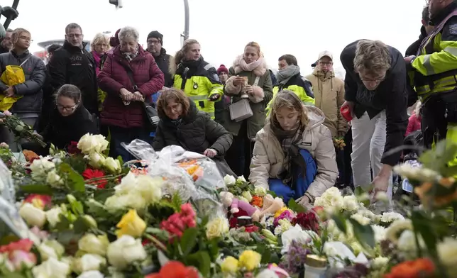 Flowers are placed by people outside St. John's Church near a Christmas Market, where a car drove into a crowd on Friday evening, in Magdeburg, Germany, Saturday, Dec. 21, 2024. (AP Photo/Ebrahim Noorozi)