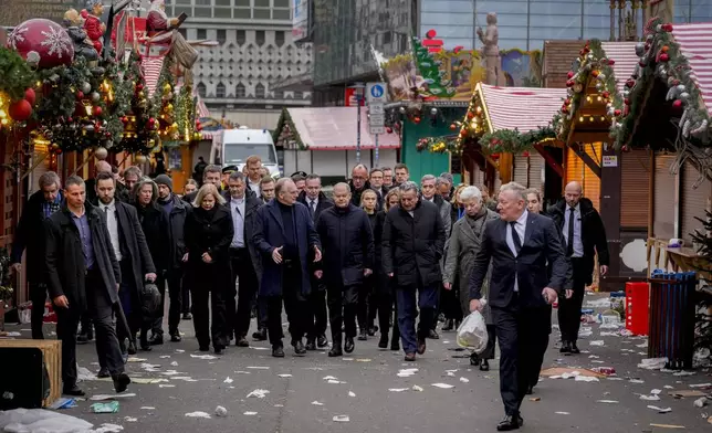 German Chancellor Olaf Scholz, centre, walks over a Christmas Market, where a car drove into a crowd on Friday evening, in Magdeburg, Germany, Saturday, Dec. 21, 2024. (AP Photo/Michael Probst)