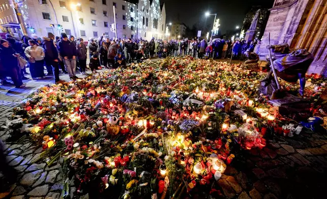 People have laid flowers and candles in front of the Johannis church close to the Christmas market, where a car drove into a crowd on Friday evening, in Magdeburg, Germany, Saturday, Dec. 21, 2024. (AP Photo/Michael Probst)