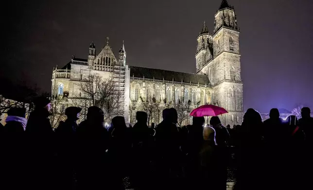 People attend a memorial service outside the cathedral close to the Christmas market, where a car drove into a crowd on Friday evening, in Magdeburg, Germany, Saturday, Dec. 21, 2024. (AP Photo/Michael Probst)