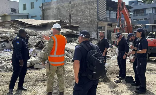 Members of Australia's Federal Police and other rescue workers stand by a collapsed building in Port Vila, Vanuatu, Thursday, Dec. 19, 2024, following a magnitude 7.3 earthquake that struck just off the coast of Vanuatu in the South Pacific Ocean, Tuesday, Dec. 17. (Australian Federal Police via AP)