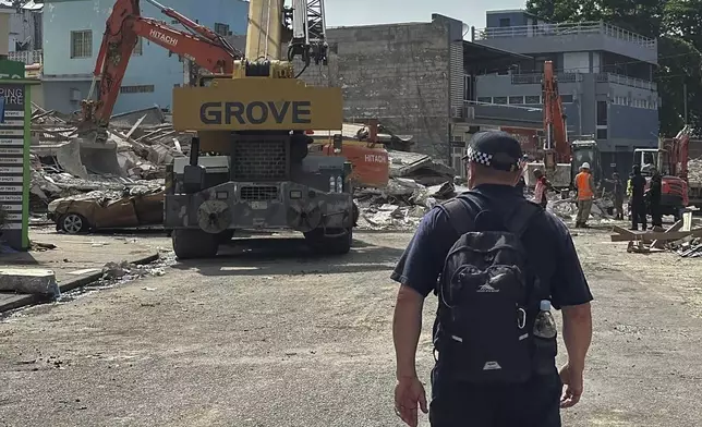 A member of Australia's Federal Police stands by a collapsed building in Port Vila, Vanuatu, Thursday, Dec. 19, 2024, following a magnitude 7.3 earthquake that struck off the coast of Vanuatu in the South Pacific Ocean, Tuesday, Dec. 17. (Australian Federal Police via AP)