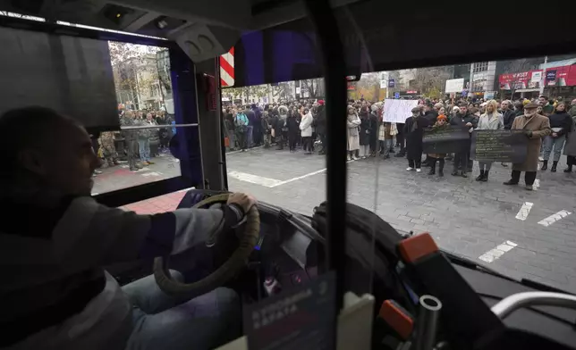 People stopping traffic stand in silence to commemorate the 15 victims of a railway roof collapse six weeks ago, demand accountability for the tragedy, in Belgrade, Serbia, Friday, Dec. 13, 2024. (AP Photo/Darko Vojinovic)