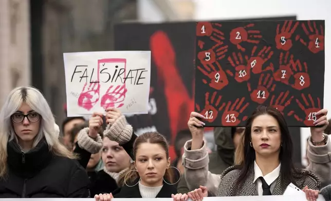 People stopping traffic hold placards and stand in silence to commemorate the 15 victims of a railway roof collapse six weeks ago, demand accountability for the tragedy, in Belgrade, Serbia, Friday, Dec. 13, 2024. (AP Photo/Darko Vojinovic)