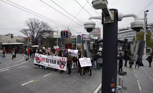 People hold a banner that reads "You have blood on your hands" and stop traffic during a silent protest to commemorate the 15 victims of a railway roof collapse six weeks ago, demand accountability for the tragedy, in Belgrade, Serbia, Friday, Dec. 13, 2024. (AP Photo/Darko Vojinovic)