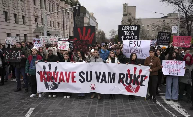 People hold a banner that reads "You have blood on your hands" and stop traffic during a silent protest to commemorate the 15 victims of a railway roof collapse six weeks ago, demand accountability for the tragedy, in Belgrade, Serbia, Friday, Dec. 13, 2024. (AP Photo/Darko Vojinovic)