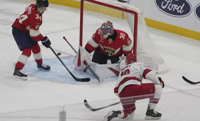 Florida Panthers goaltender Spencer Knight (30) deflects a shot by Carolina Hurricanes center Jack Drury (18) during the first period of an NHL hockey game, Saturday, Nov. 30, 2024, in Sunrise, Fla. (AP Photo/Marta Lavandier)