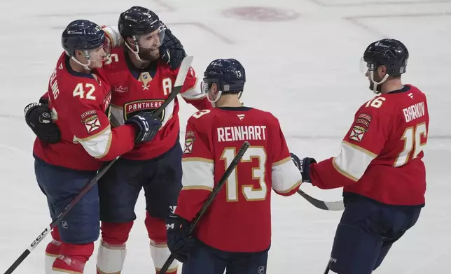 Florida Panthers defenseman Aaron Ekblad (5) is congratulated by his teammates after scoring a goal during the second period of an NHL hockey game against the Carolina Hurricanes, Saturday, Nov. 30, 2024, in Sunrise, Fla. (AP Photo/Marta Lavandier)