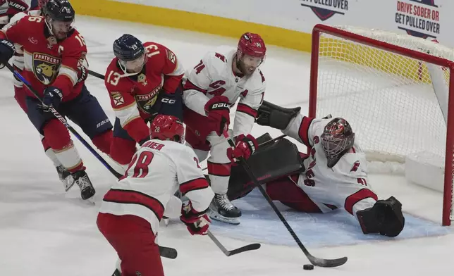 Carolina Hurricanes goaltender Spencer Martin (41) and defenseman Jaccob Slavin (74) defend against a shot by Florida Panthers center Sam Reinhart (13) during the second period of an NHL hockey game, Saturday, Nov. 30, 2024, in Sunrise, Fla. (AP Photo/Marta Lavandier)