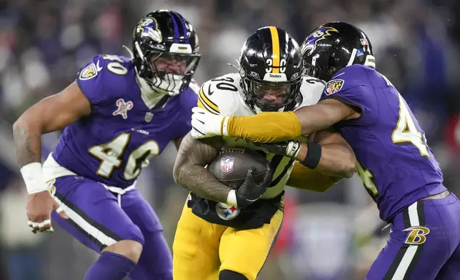 Pittsburgh Steelers running back Jaylen Warren (30) runs with the ball as Baltimore Ravens cornerback Marlon Humphrey, right, and linebacker Malik Harrison try to stop him during the first half of an NFL football game, Saturday, Dec. 21, 2024, in Baltimore. (AP Photo/Stephanie Scarbrough)