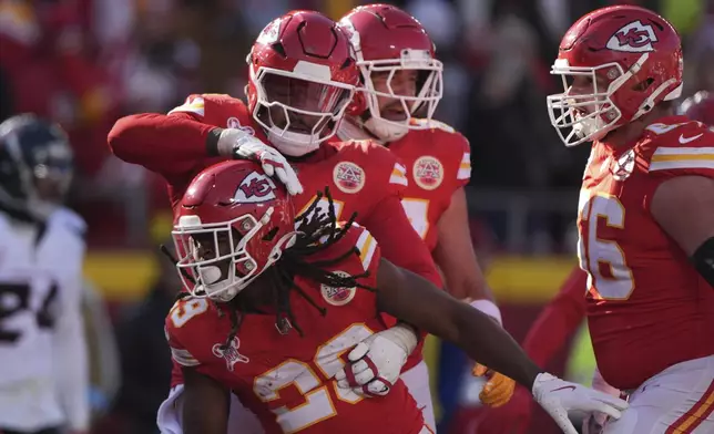 Kansas City Chiefs running back Kareem Hunt, front, is congratulated by teammates after scoring during the first half of an NFL football game against the Houston Texans Saturday, Dec. 21, 2024, in Kansas City, Mo. (AP Photo/Charlie Riedel)