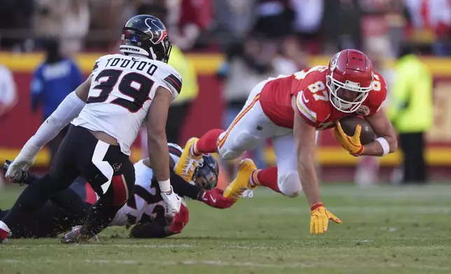 Kansas City Chiefs tight end Travis Kelce (87) gains a first down as he is stopped by Houston Texans safety Eric Murray (23) and linebacker Henry To'oTo'o (39) during the second half of an NFL football game Saturday, Dec. 21, 2024, in Kansas City, Mo. (AP Photo/Charlie Riedel)