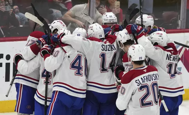 Montreal Canadiens players surround goaltender Jakub Dobes, not seen, after the Canadiens defeated the Florida Panthers 4-0 in an NHL hockey game, Saturday, Dec. 28, 2024, in Sunrise, Fla. (AP Photo/Lynne Sladky)