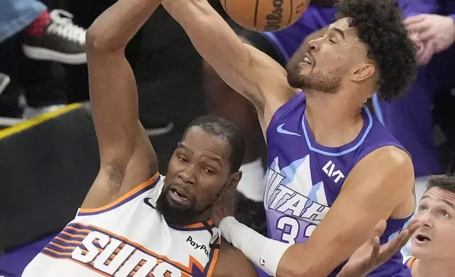 Utah Jazz guard Johnny Juzang, right, defends against Phoenix Suns forward Kevin Durant (35) as he pulls down a rebound during the second half of an NBA basketball game Friday, Dec. 13, 2024, in Salt Lake City. (AP Photo/Rick Bowmer)