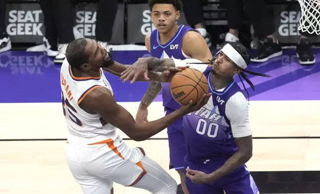 Utah Jazz guard Jordan Clarkson (00) fouls Phoenix Suns forward Kevin Durant, left, who drives to the basket during the second half of an NBA basketball game Friday, Dec. 13, 2024, in Salt Lake City. (AP Photo/Rick Bowmer)