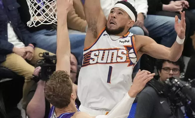 Phoenix Suns guard Devin Booker (1) goes to the basket as Utah Jazz forward Lauri Markkanen (23) defends during the first half of an NBA basketball game Friday, Dec. 13, 2024, in Salt Lake City. (AP Photo/Rick Bowmer)