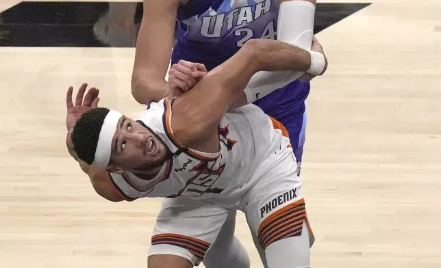 Phoenix Suns guard Devin Booker (1) and Utah Jazz center Walker Kessler (24) battle for position under the boards during the first half of an NBA basketball game Friday, Dec. 13, 2024, in Salt Lake City. (AP Photo/Rick Bowmer)