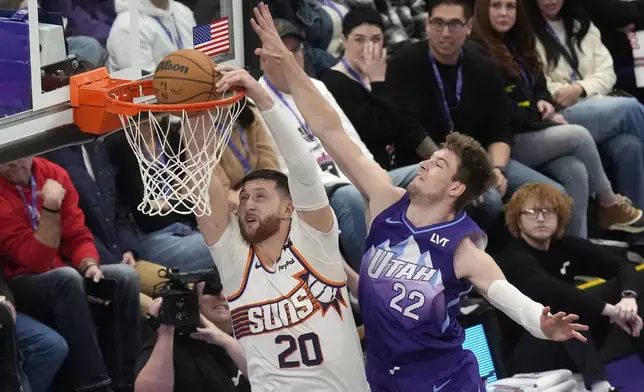 Phoenix Suns center Jusuf Nurkic (20) dunks against Utah Jazz forward Kyle Filipowski (22) during the first half of an NBA basketball game Friday, Dec. 13, 2024, in Salt Lake City. (AP Photo/Rick Bowmer)