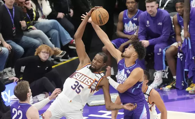 Utah Jazz guard Johnny Juzang, right, defends against Phoenix Suns forward Kevin Durant (35) as he pulls down a rebound during the second half of an NBA basketball game Friday, Dec. 13, 2024, in Salt Lake City. (AP Photo/Rick Bowmer)