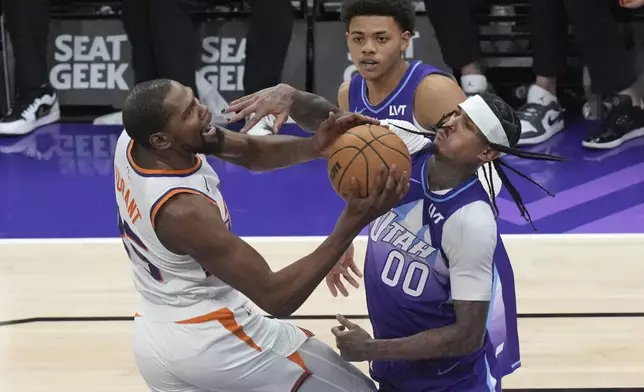 Utah Jazz guard Jordan Clarkson (00) fouls Phoenix Suns forward Kevin Durant, left, who drives to the basket during the second half of an NBA basketball game Friday, Dec. 13, 2024, in Salt Lake City. (AP Photo/Rick Bowmer)