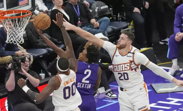 Utah Jazz guard Collin Sexton (2) goes to the basket as Phoenix Suns' Jusuf Nurkic (20) and Royce O'Neale (00) defend during the second half of an NBA basketball game Friday, Dec. 13, 2024, in Salt Lake City. (AP Photo/Rick Bowmer)