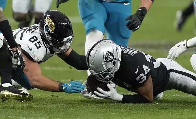 Las Vegas Raiders safety Thomas Harper (34) recovers a rumble against Jacksonville Jaguars tight end Brenton Strange (85) during the first half of an NFL football game Sunday, Dec. 22, 2024, in Las Vegas. (AP Photo/John Locher)