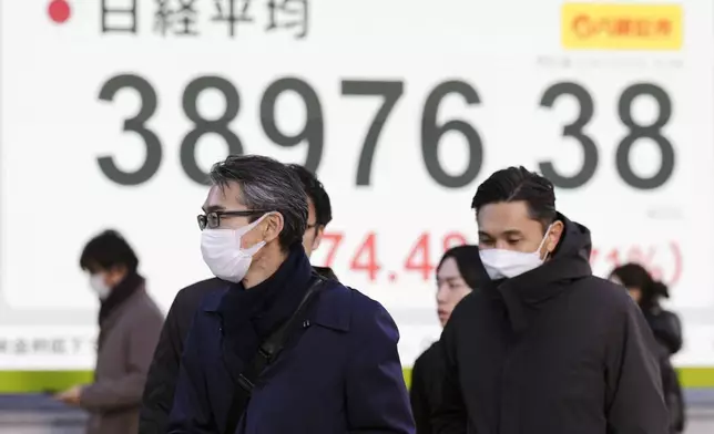 People walk in front of an electronic stock board showing Japan's Nikkei index at a securities firm Monday, Dec. 23, 2024, in Tokyo. (AP Photo/Eugene Hoshiko)