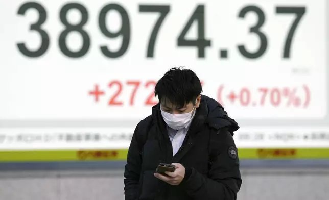 A person walks in front of an electronic stock board showing Japan's Nikkei index at a securities firm Monday, Dec. 23, 2024, in Tokyo. (AP Photo/Eugene Hoshiko)