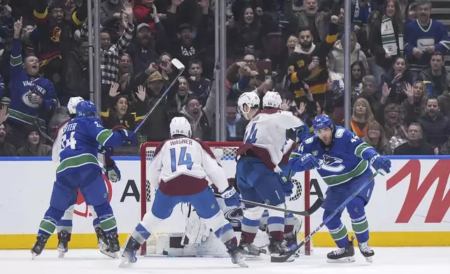 Vancouver Canucks' Kiefer Sherwood, right, celebrates after his goal against Colorado Avalanche goalie MacKenzie Blackwood, center back, during the first period of an NHL hockey game in Vancouver, British Columbia, Monday, Dec. 16, 2024. (Darryl Dyck/The Canadian Press via AP)