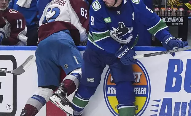 Colorado Avalanche's Artturi Lehkonen (62) loses his helmet after being checked by Vancouver Canucks' J.T. Miller (9) during the third period of an NHL hockey game in Vancouver, Monday, Dec. 16, 2024. (Darryl Dyck/The Canadian Press via AP)