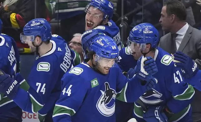 Vancouver Canucks' Kiefer Sherwood (44), Vincent Desharnais (73), Jake DeBrusk (74) and Noah Juulsen (47) celebrate Sherwood's third goal against the Colorado Avalanche during the third period of an NHL hockey game in Vancouver, Monday, Dec. 16, 2024. (Darryl Dyck/The Canadian Press via AP)