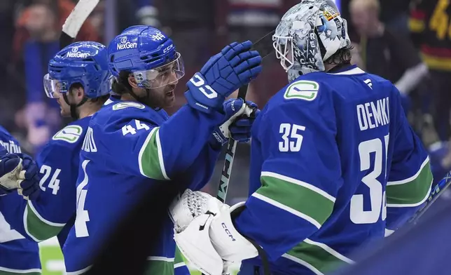 Vancouver Canucks' Kiefer Sherwood, left, and goalie Thatcher Demko celebrate after Vancouver defeated the Colorado Avalanche during an NHL hockey game in Vancouver, Monday, Dec. 16, 2024. (Darryl Dyck/The Canadian Press via AP)