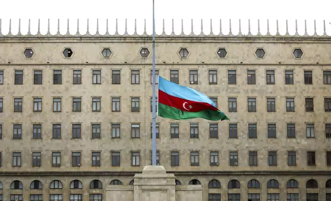 Azerbaijan's national flag at half-mast in the memory of victims of the Azerbaijan Airlines' Embraer 190 that crashed near the Kazakhstan's airport of Aktau, is seen in front of a Government's building in the center of Baku, Azerbaijan, Thursday, Dec. 26, 2024. (AP Photo/Aziz Karimov)