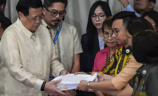 House Secretary General, Reginald Velasco, left, receives a second impeachment complaint filed against Philippine Vice President Sara Duterte on Wednesday Dec. 4, 2024 at the House of Representatives in Quezon City, Philippines. (AP Photo/Aaron Favila)