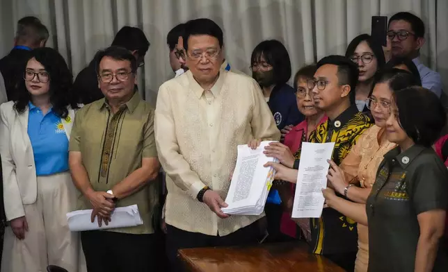 House Secretary General, Reginald Velasco, center, receives a second impeachment complaint filed against Philippine Vice President Sara Duterte by a group led by left-wing activists on Wednesday Dec. 4, 2024 at the House of Representatives in Quezon City, Philippines. (AP Photo/Aaron Favila)