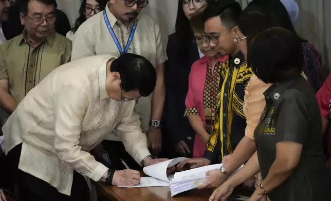 House Secretary General, Reginald Velasco, left, signs a document as a second impeachment complaint is filed against Philippine Vice President Sara Duterte by a group led by left-wing activists on Wednesday Dec. 4, 2024 at the House of Representatives in Quezon City, Philippines. (AP Photo/Aaron Favila)