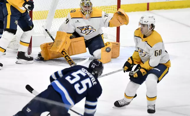 Nashville Predators goaltender Juuse Saros keeps his eye on the puck as Winnipeg Jets' Mark Scheifele (55) gets a shot away during the first period of an NHL hockey game in Winnipeg, Manitoba, Monday, Dec. 30, 2024. (Fred Greenslade/The Canadian Press via AP)