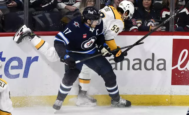 Nashville Predators' Roman Josi (59) is checked by Winnipeg Jets' Adam Lowry (17) during the first period of an NHL hockey game in Winnipeg, Manitoba, Monday, Dec. 30, 2024. (Fred Greenslade/The Canadian Press via AP)