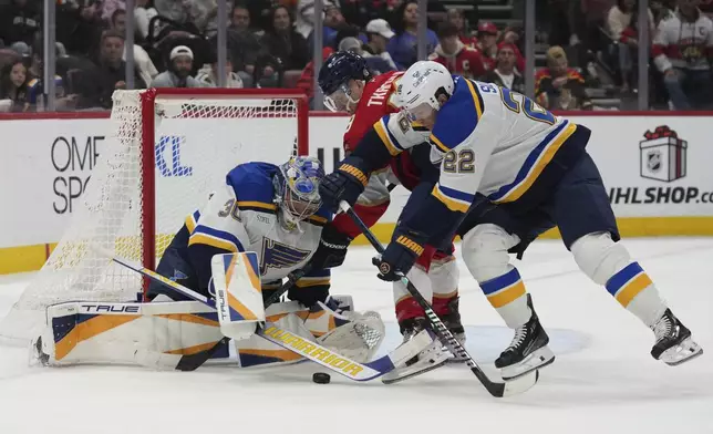 St. Louis Blues goaltender Joel Hofer (30) and defenseman Ryan Suter (22) defend the goal against Florida Panthers left wing Matthew Tkachuk (19) during the second period of an NHL hockey game, Friday, Dec. 20, 2024, in Sunrise, Fla. (AP Photo/Lynne Sladky)