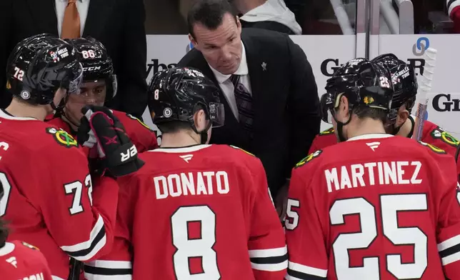 Chicago Blackhawks head coach Luke Richardson, center top, talks to his players during the third period of an NHL hockey game against the Columbus Blue Jackets in Chicago, Sunday, Dec.1, 2024. (AP Photo/Nam Y. Huh)