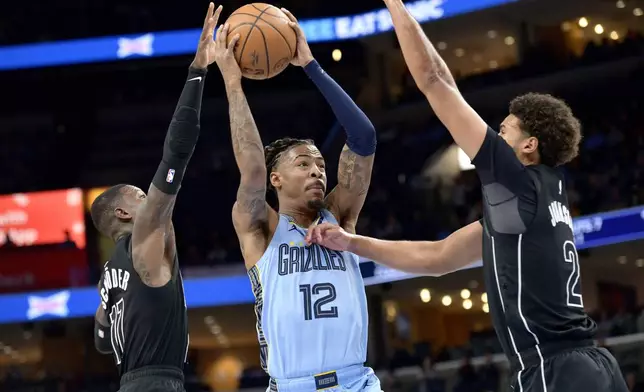 Memphis Grizzlies guard Ja Morant (12) shoots between Brooklyn Nets guard Dennis Schroder (17) and forward Cameron Johnson (2) in the first half of an NBA basketball game Friday, Dec. 13, 2024, in Memphis, Tenn. (AP Photo/Brandon Dill)