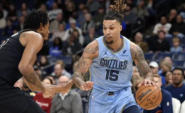 Memphis Grizzlies forward Brandon Clarke (15) handles the ball against Brooklyn Nets center Nic Claxton in the first half of an NBA basketball game Friday, Dec. 13, 2024, in Memphis, Tenn. (AP Photo/Brandon Dill)