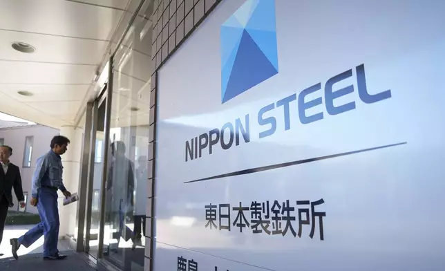 A staff enters doorway next to Nippon Steel logo at the company's Kashima Plant in Kashima, Japan on Friday, Dec. 6, 2024. (AP Photo/Ayaka McGill)
