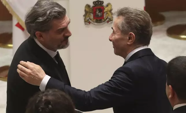 Georgian Dream party founder Bidzina Ivanishvili, right, embraces Georgian President-elect Mikheil Kavelashvili, left, at his swearing-in ceremony at the Georgian Parliament in Tbilisi, Georgia, Sunday, Dec. 29, 2024. (Irakli Gedenidze/Pool Photo via AP)